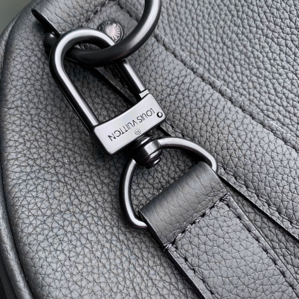 Louis Vuitton strap clasp and ring hardware on dark gray pebble-grain leather.
