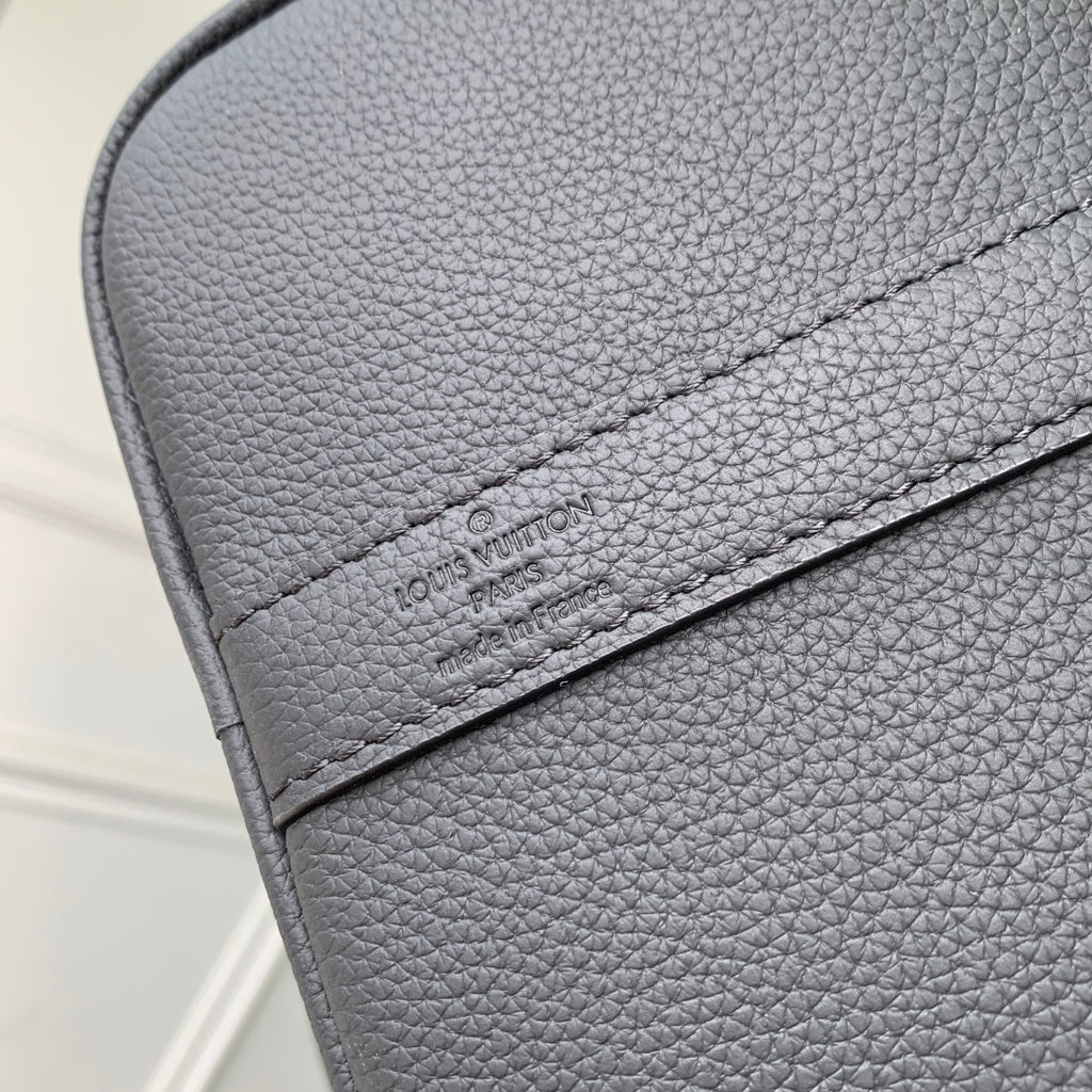 Louis Vuitton logo patch on dark gray pebble-grain leather flap with stitched edge.