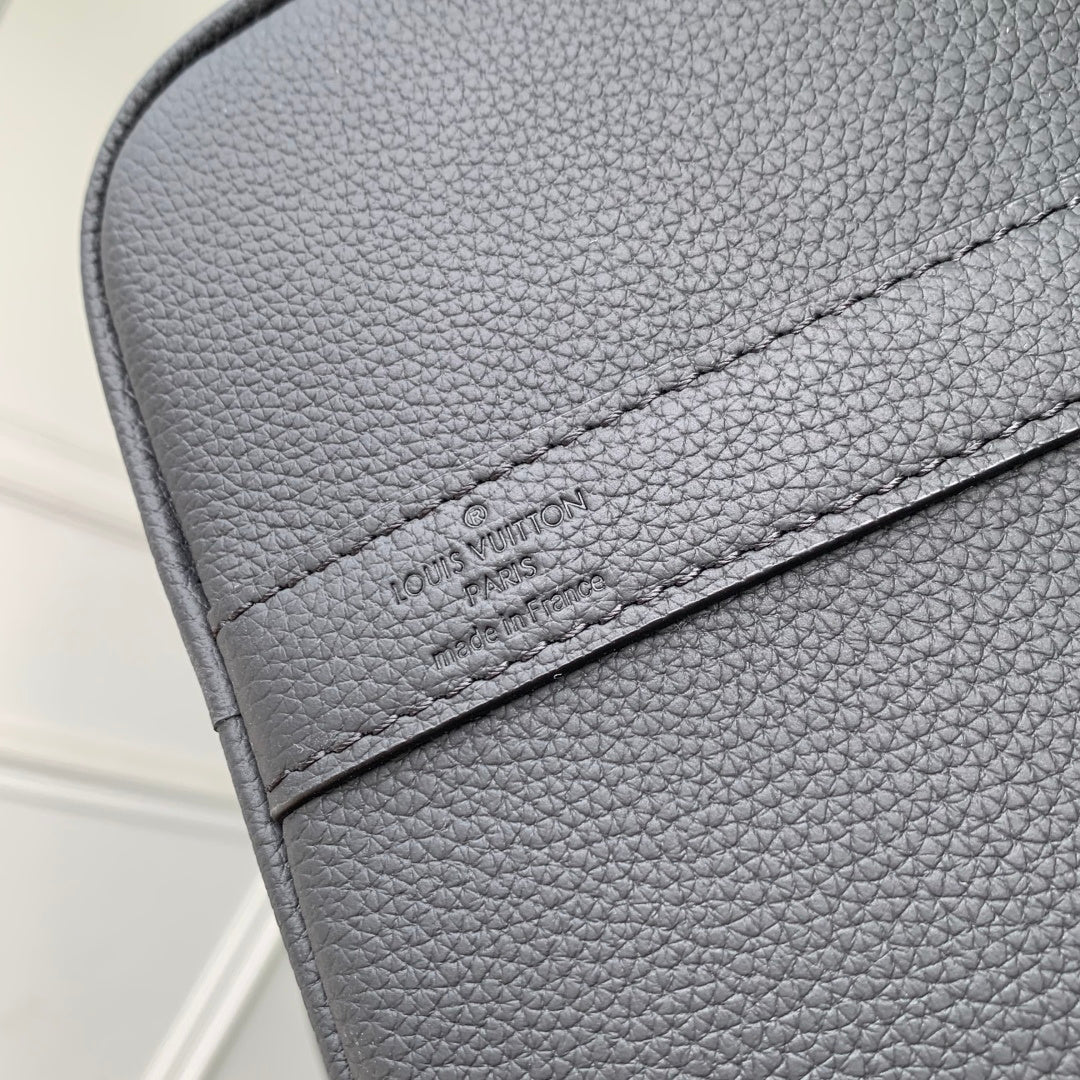 Louis Vuitton logo patch on dark gray pebble-grain leather flap with stitched edge.