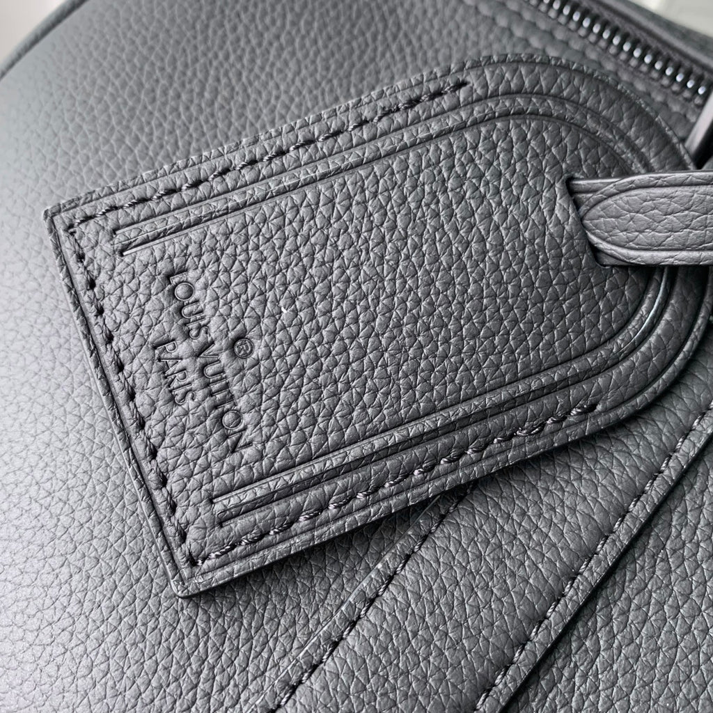 Louis Vuitton leather detail with embossed stitching and zipper track on dark gray leather.