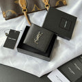 Black textured small wallet bag with gold YSL logo, snap-style top closure