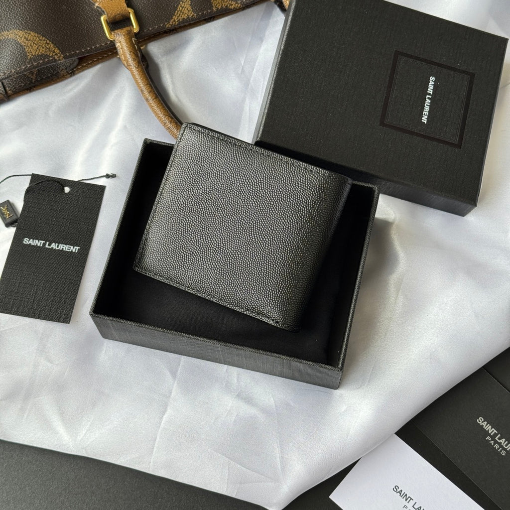 Small textured leather card holder wallet with YSL logo, laid over gift packaging