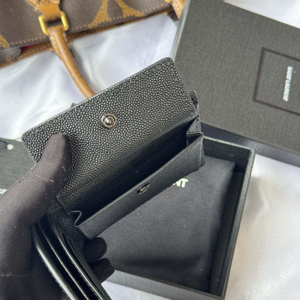 Textured dark small crossbody-style bag with snap flap, visible opening