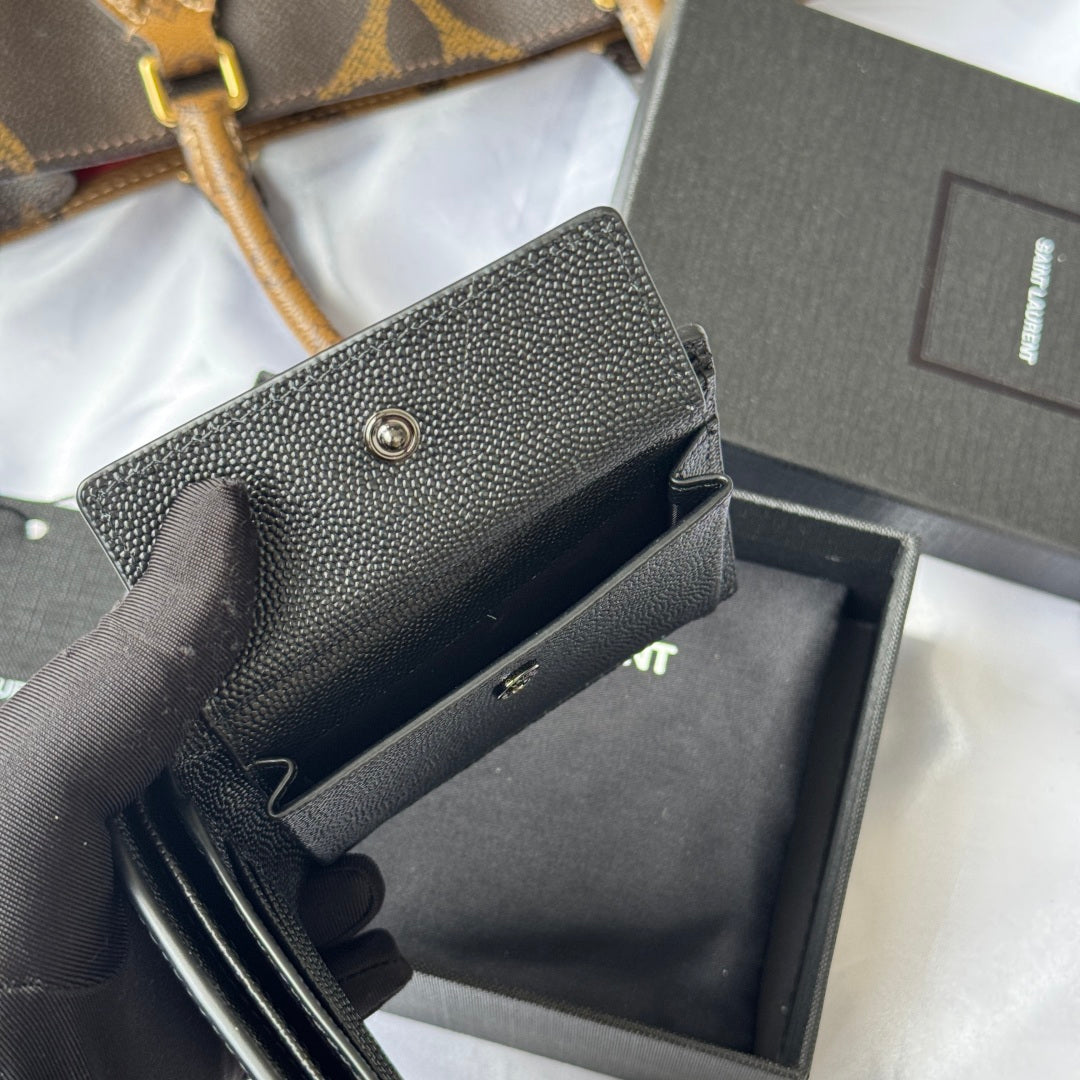Textured dark small crossbody-style bag with snap flap, visible opening