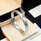 Louis Vuitton engraved silver cuff bracelet with decorative emblem detail on side