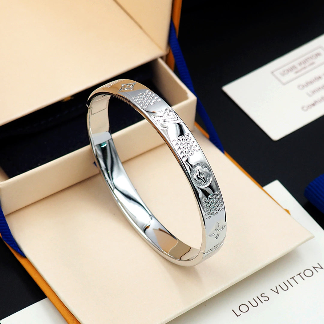 Louis Vuitton engraved silver cuff bracelet with decorative emblem detail on side