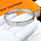 Louis Vuitton engraved silver cuff bracelet on a soft cushion, glossy polished finish