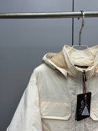 Light beige hooded jacket with front zipper, patch pocket, and Moncler emblem