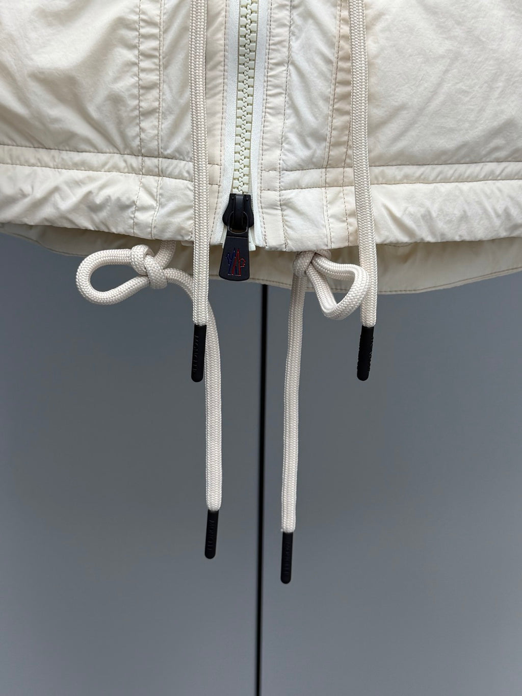 Light beige jacket with dual hood drawstrings and cord toggles