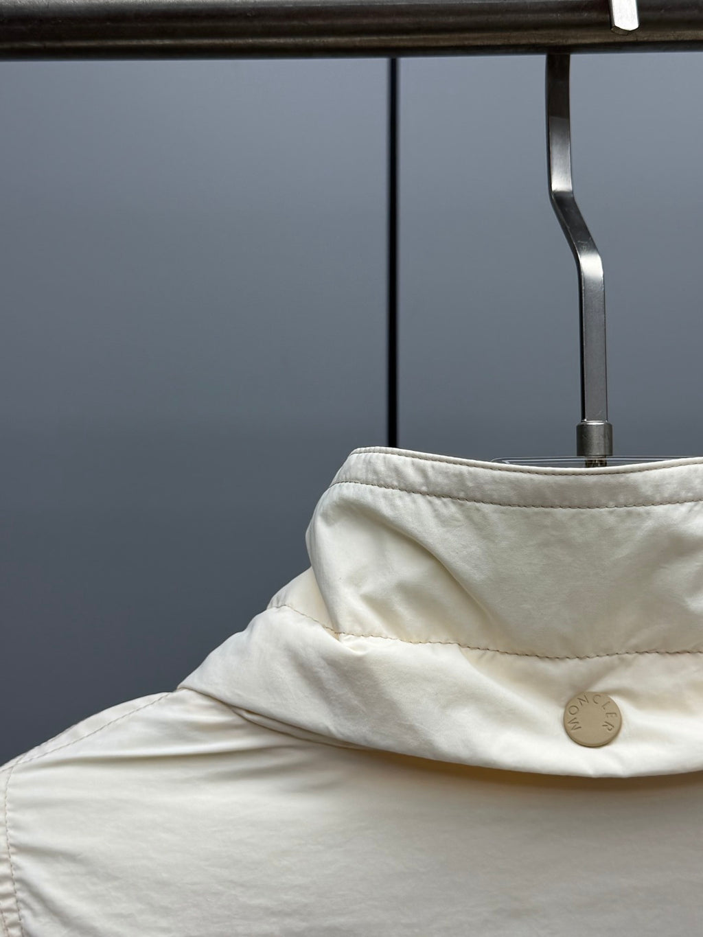 Cream puffer jacket hood detail with snap button at collar