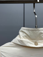 Cream puffer jacket hood detail with snap button at collar