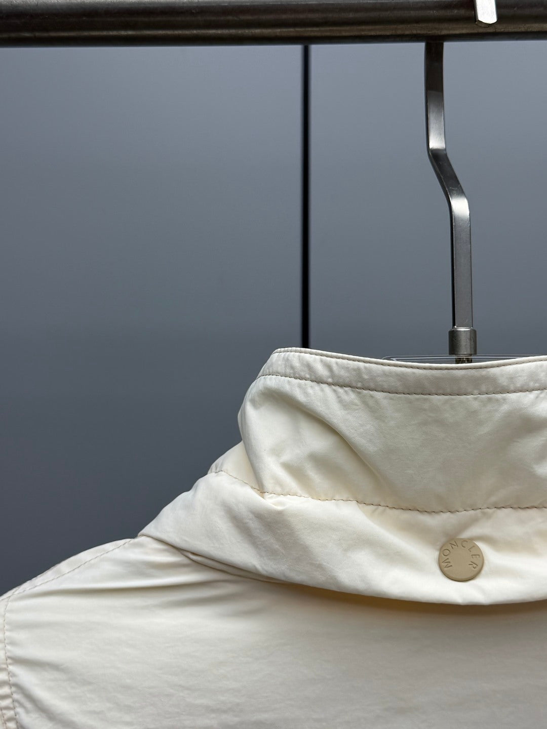 Cream puffer jacket hood detail with snap button at collar