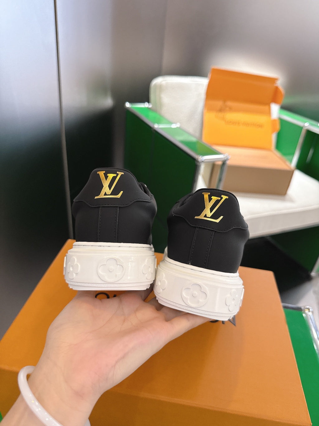 Louis Vuitton sneakers back view, black uppers with LV logo, white textured sole