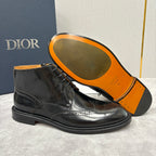 Black leather lace-up ankle boot with orange outsole; brogue toe and lace closure