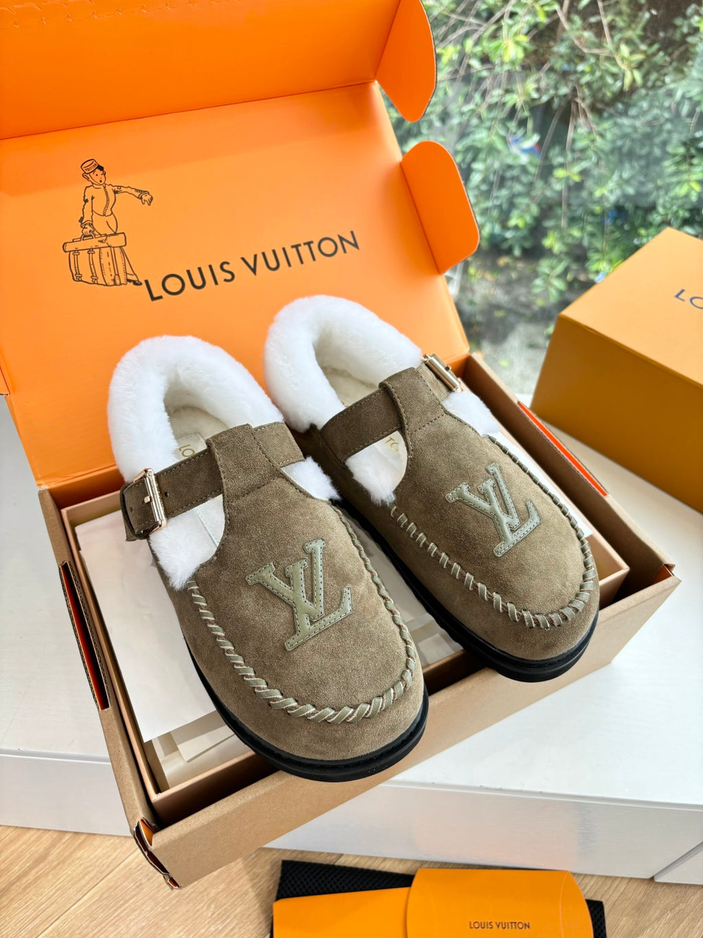 Taupe suede moccasin shoes with white shearling lining and buckle strap