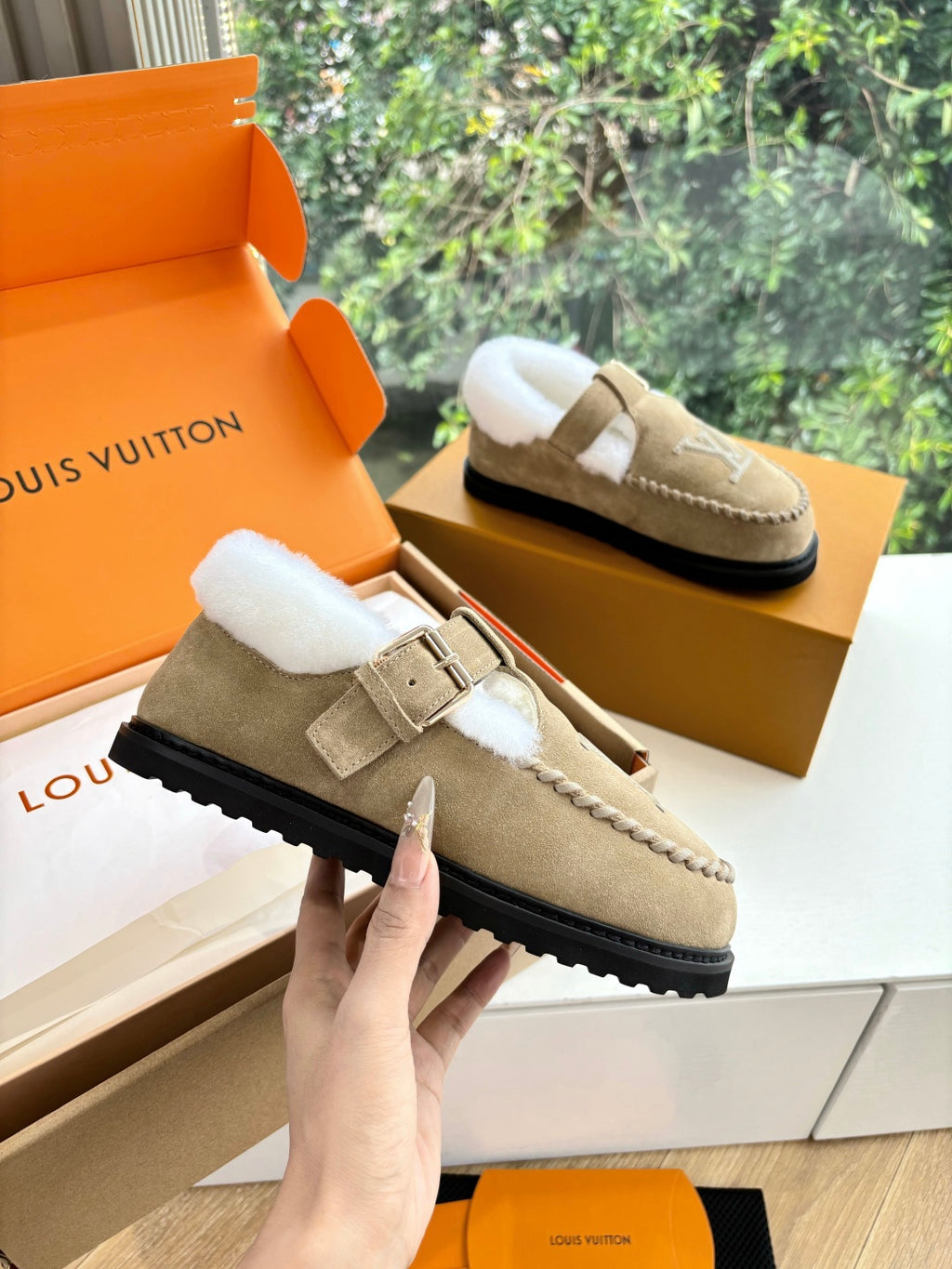 Tan suede shearling-lined loafer with buckle strap and Louis Vuitton monogram.