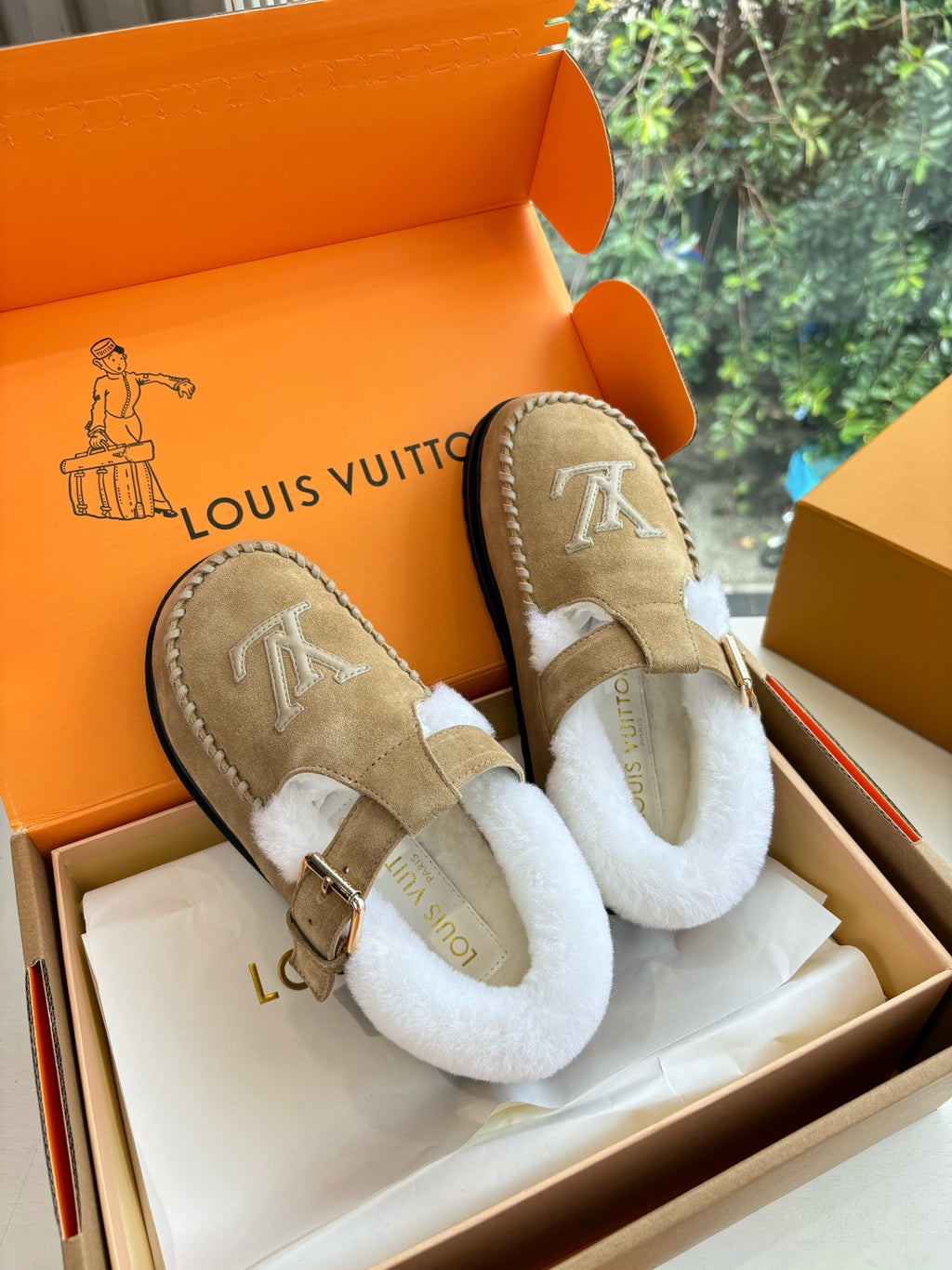 Tan suede shearling moccasin loafers with buckle strap and Louis Vuitton monogram.