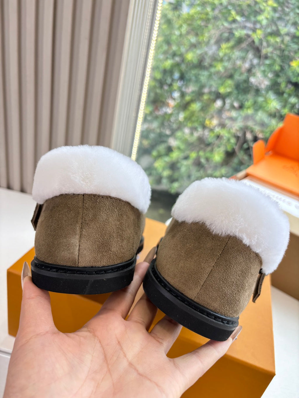 Back view of taupe suede moccasin shoes with white shearling collar and black sole