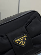Prada bag close-up: black fabric with gold Prada triangular logo patch