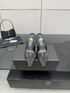 YSL black leather-look heeled pumps with gold logo detail, on display