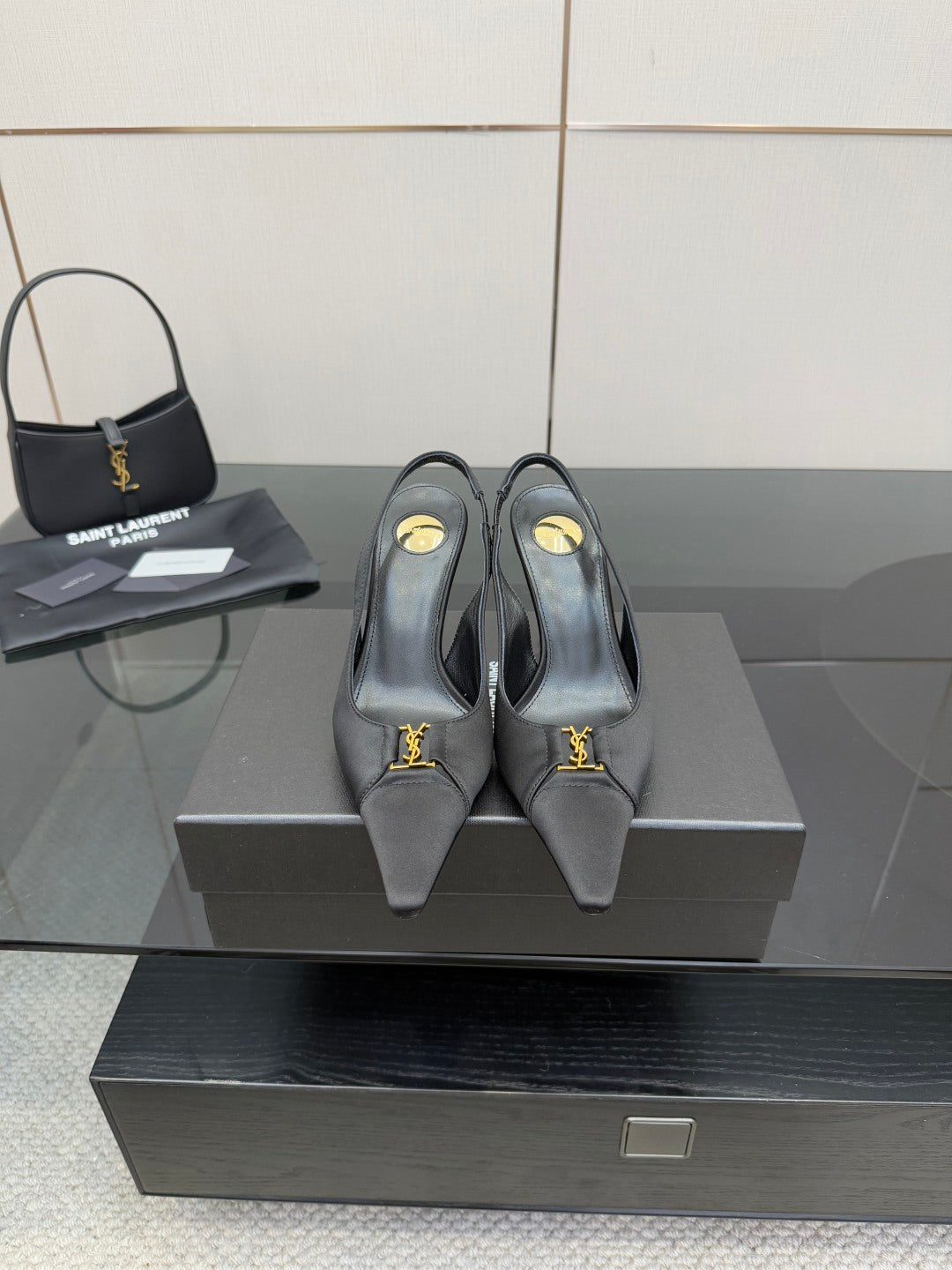 YSL black leather-look heeled pumps with gold logo detail, on display