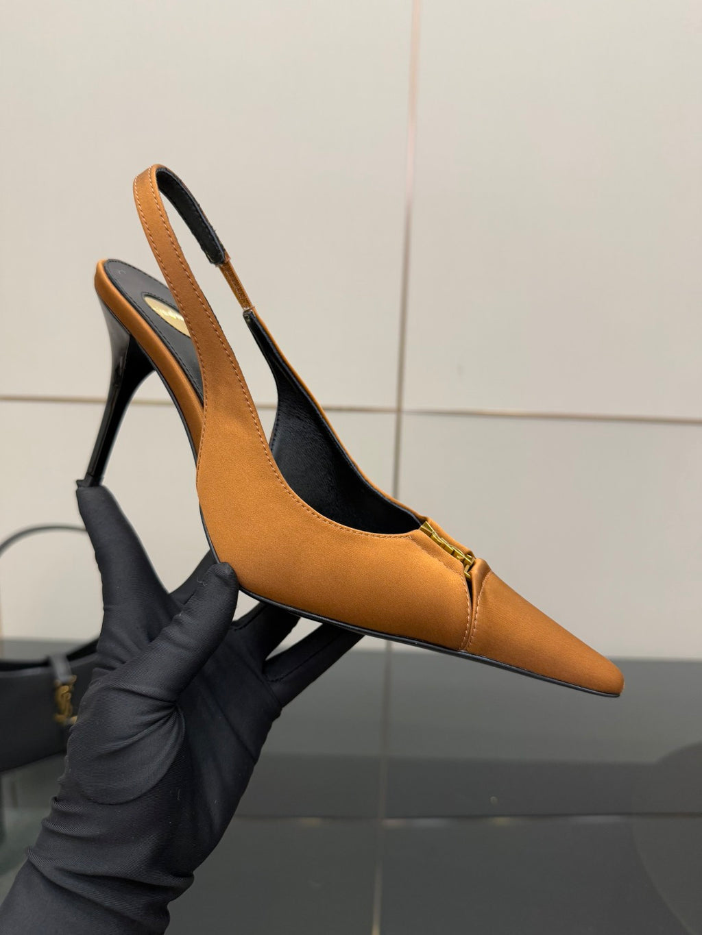 Orange slingback heels with pointed toe, black lining, and gold logo accent