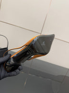 Orange slingback heel with black sole underside and gold logo accent