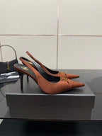 Tan leather slingback pump with thin stiletto heel and gold emblem on toe strap