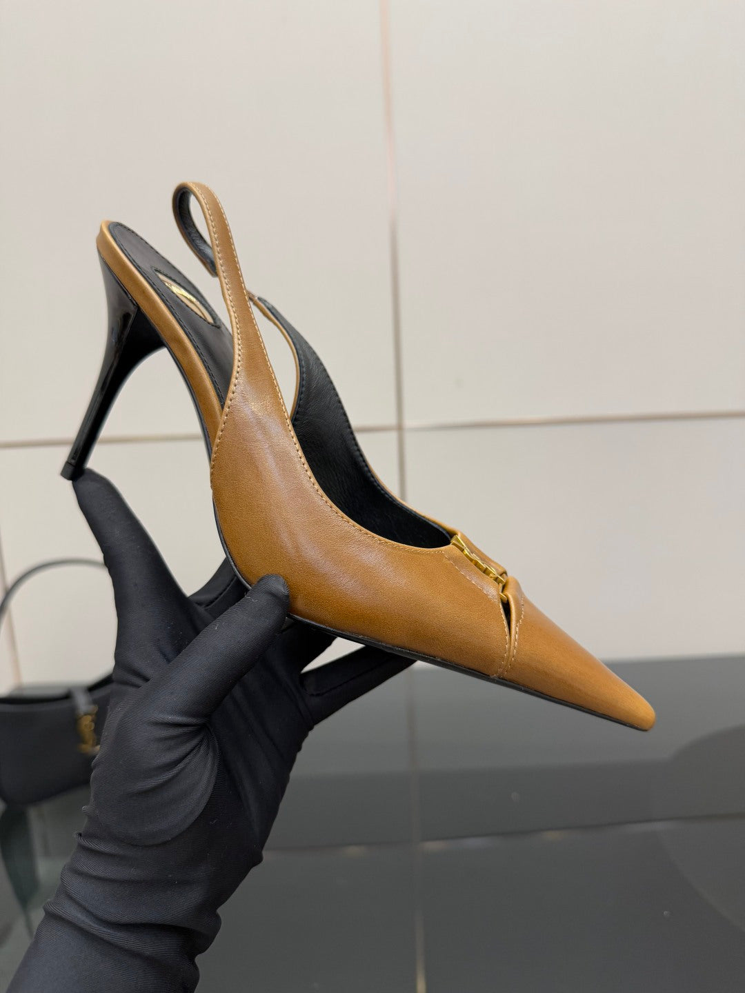 YSL ladies' tan pointed-toe high heel held in hand, stiletto heel and slingback