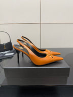 Women's orange pointed-toe stiletto heels with gold buckle detail, side view