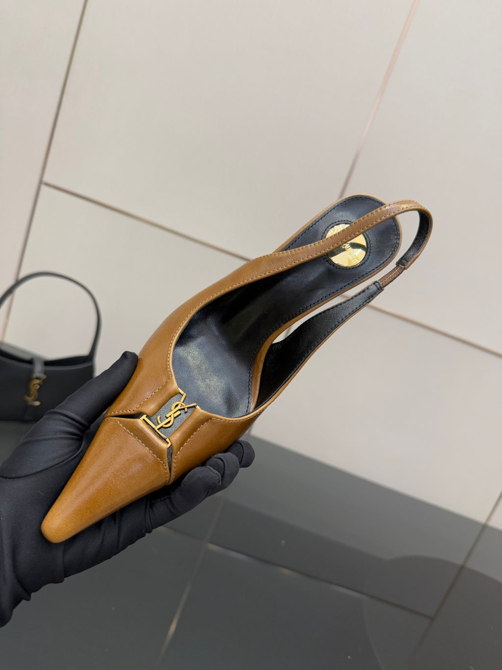 YSL ladies' tan slingback pointed-toe heel, interior view held in gloved hand