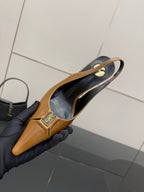 YSL ladies' tan slingback pointed-toe heel, interior view held in gloved hand