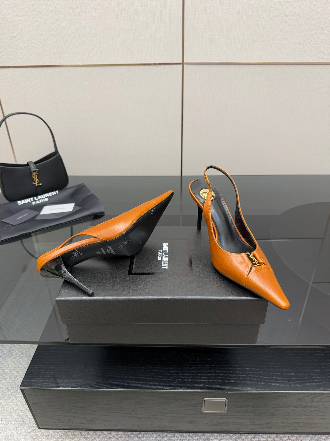 Women's orange pointed-toe stiletto heels with gold buckle detail, one shoe angled