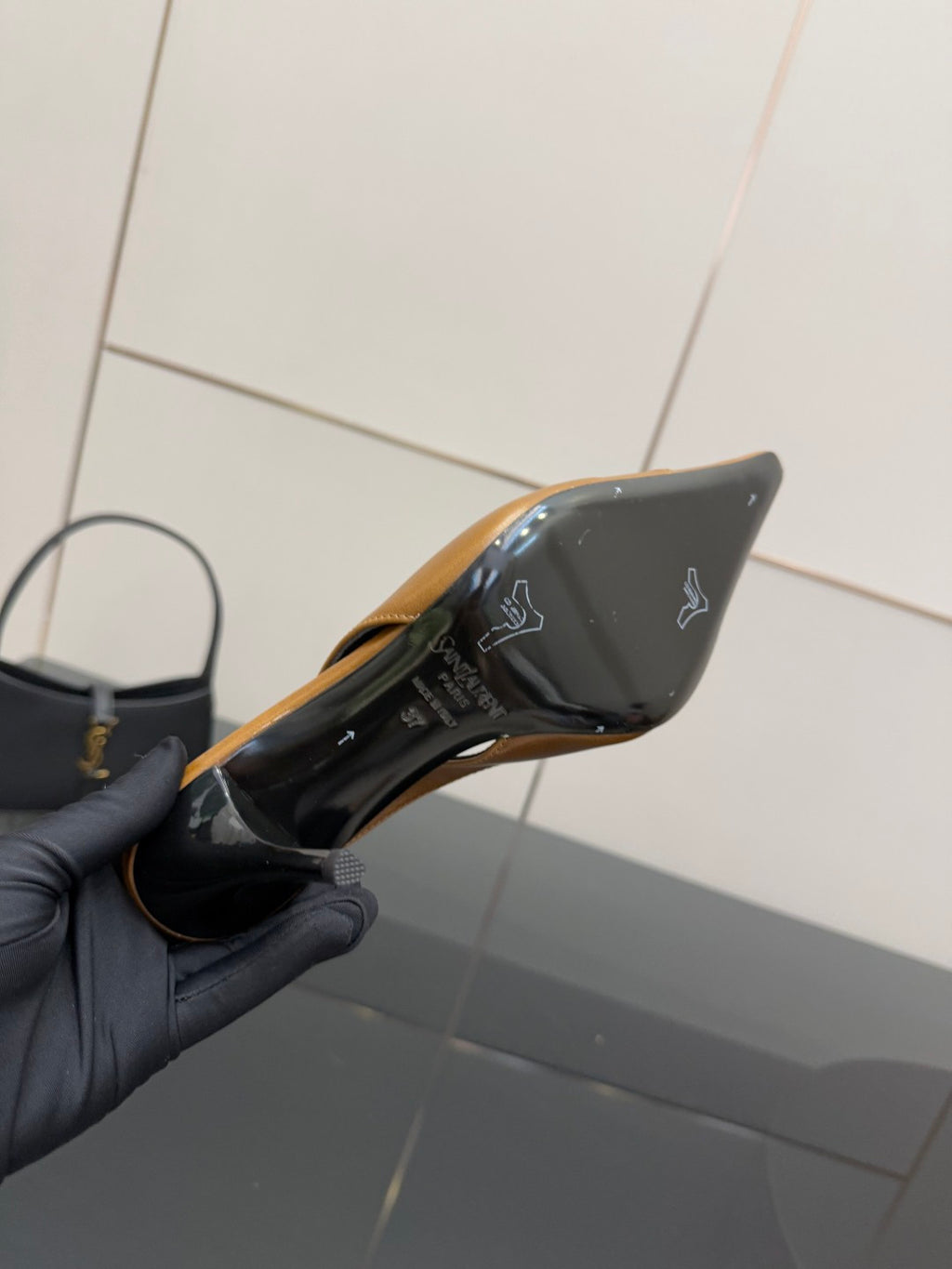 YSL ladies' heel underside close-up held in hand, showing black bottom with logo