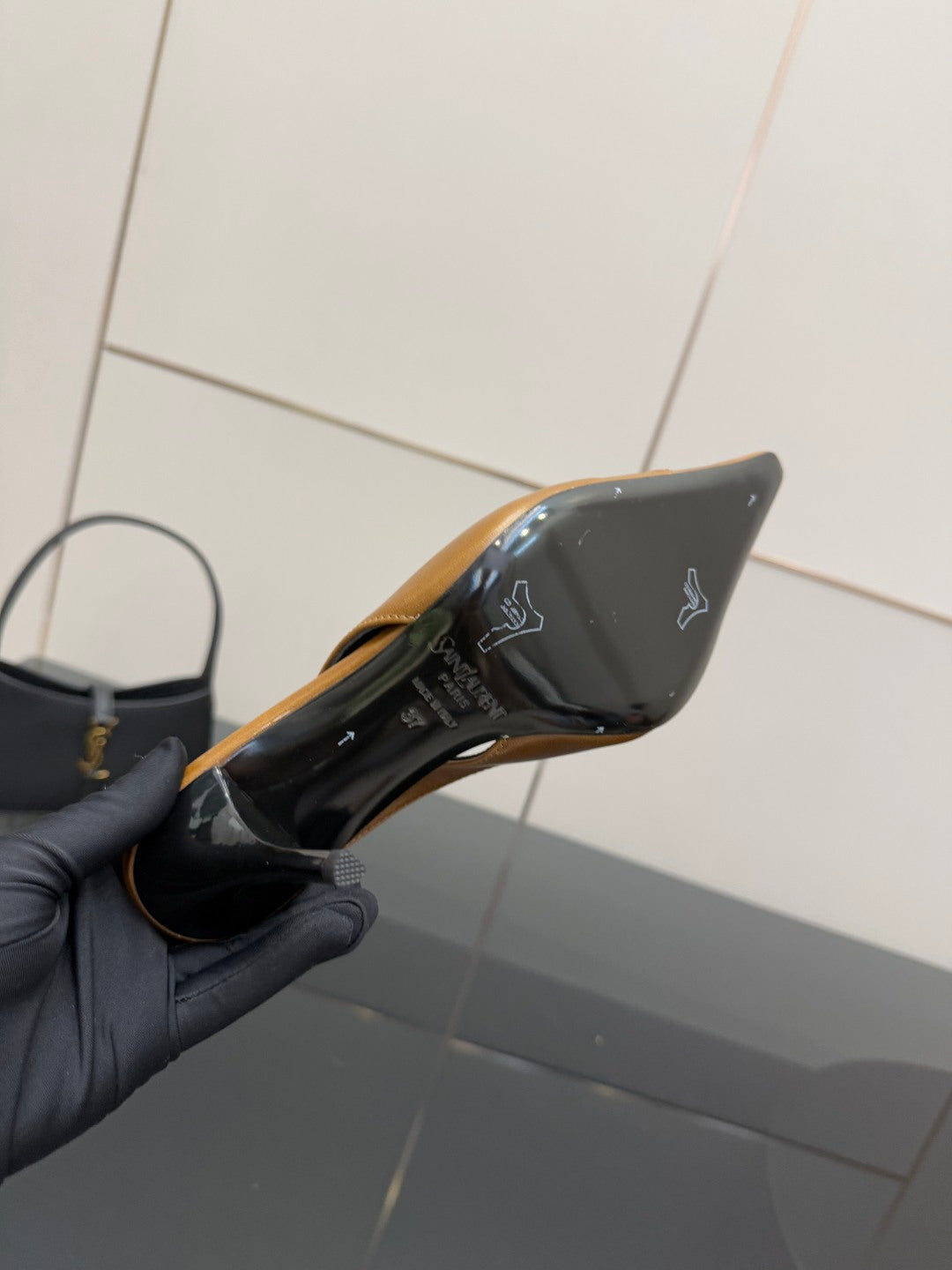 YSL ladies' heel underside close-up held in hand, showing black bottom with logo