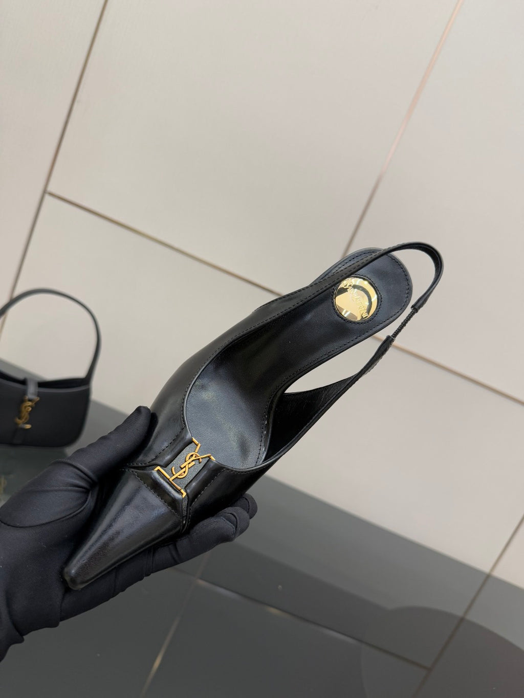YSL ladies black pointed-toe pump close-up with gold logo on strap