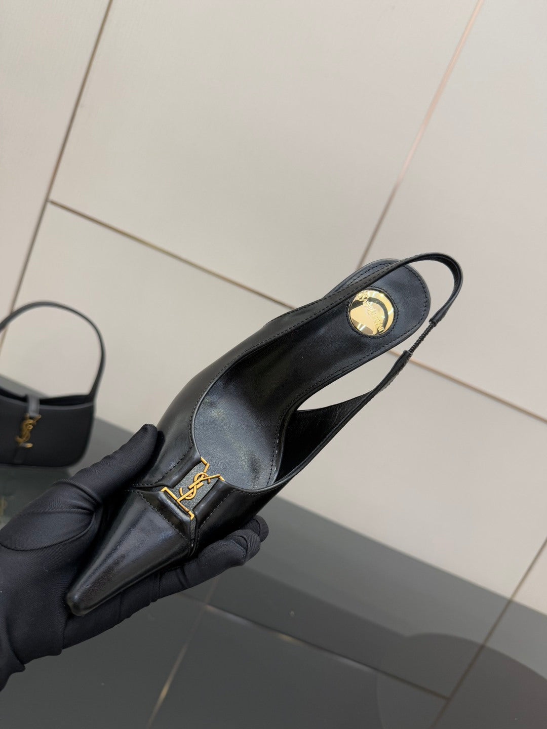 YSL ladies black pointed-toe pump close-up with gold logo on strap