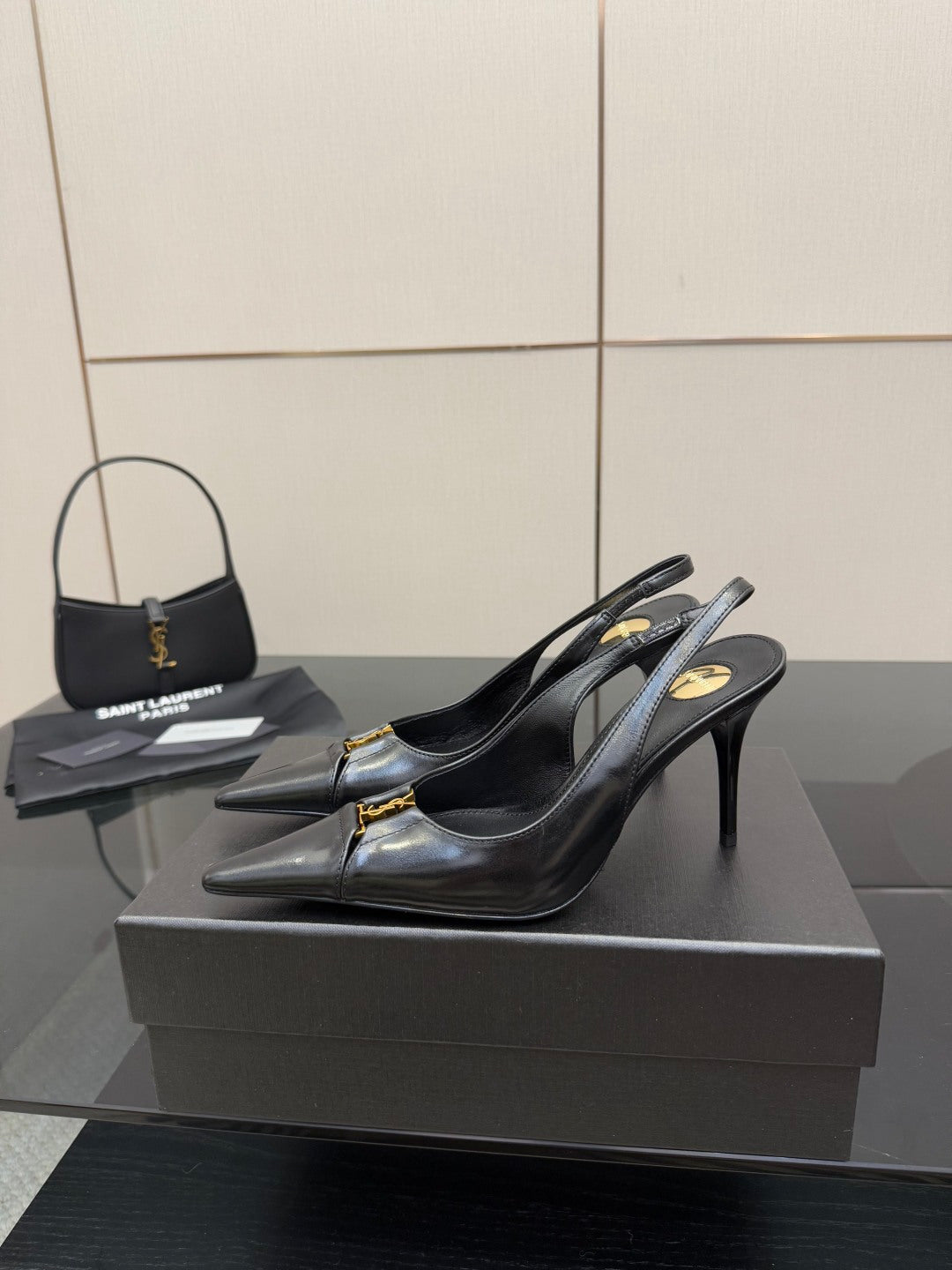 YSL ladies black slingback pumps on display with gold logo detail at toe