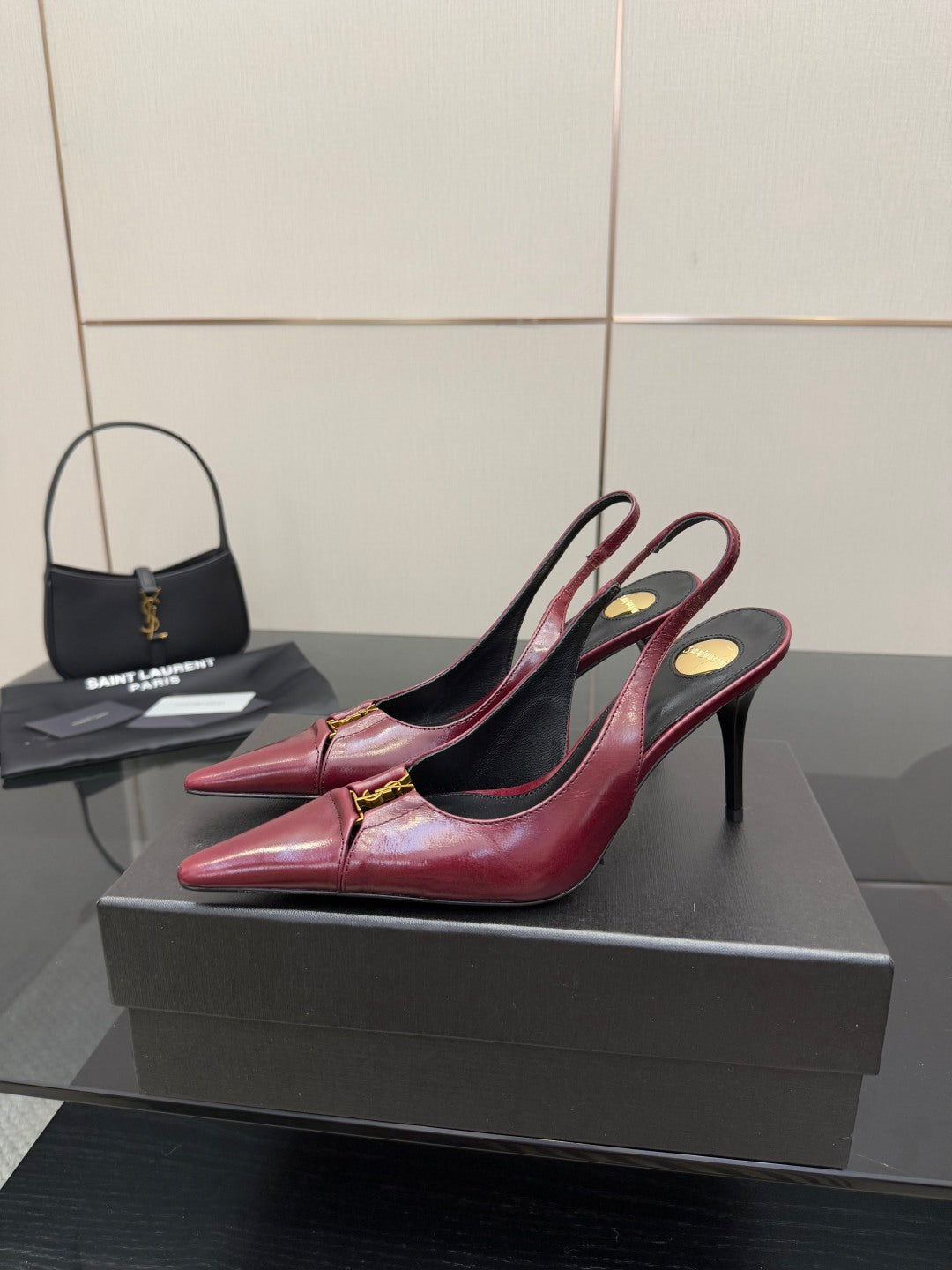 Burgundy red pointed-toe stiletto heel with gold emblem and ankle strap, front angle