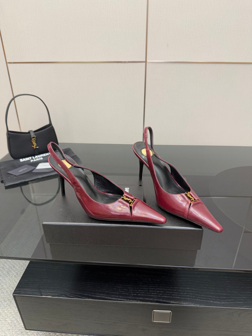 Burgundy red pointed-toe stiletto pumps with gold emblem, angled side view pair