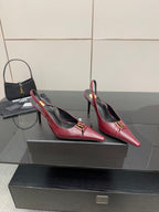 Burgundy red pointed-toe stiletto pumps with gold emblem, angled side view pair