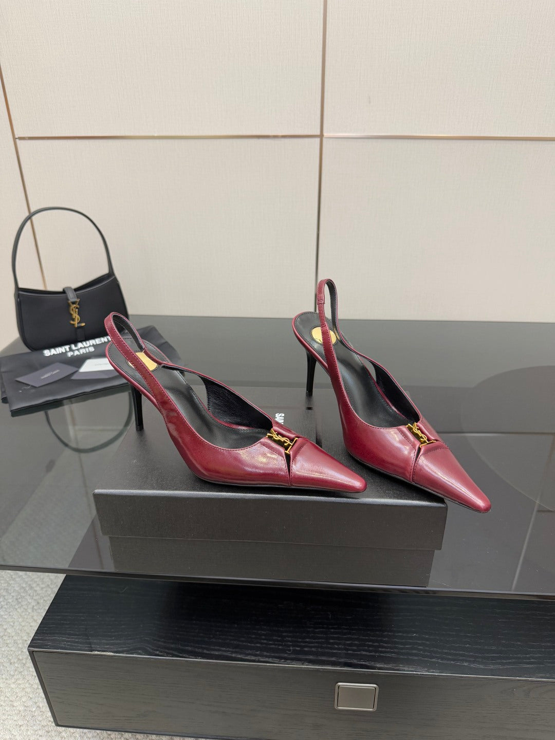 Burgundy red pointed-toe stiletto pumps with gold emblem, angled side view pair