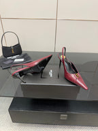 Burgundy red pointed-toe stiletto pumps with gold emblem, heel-side view