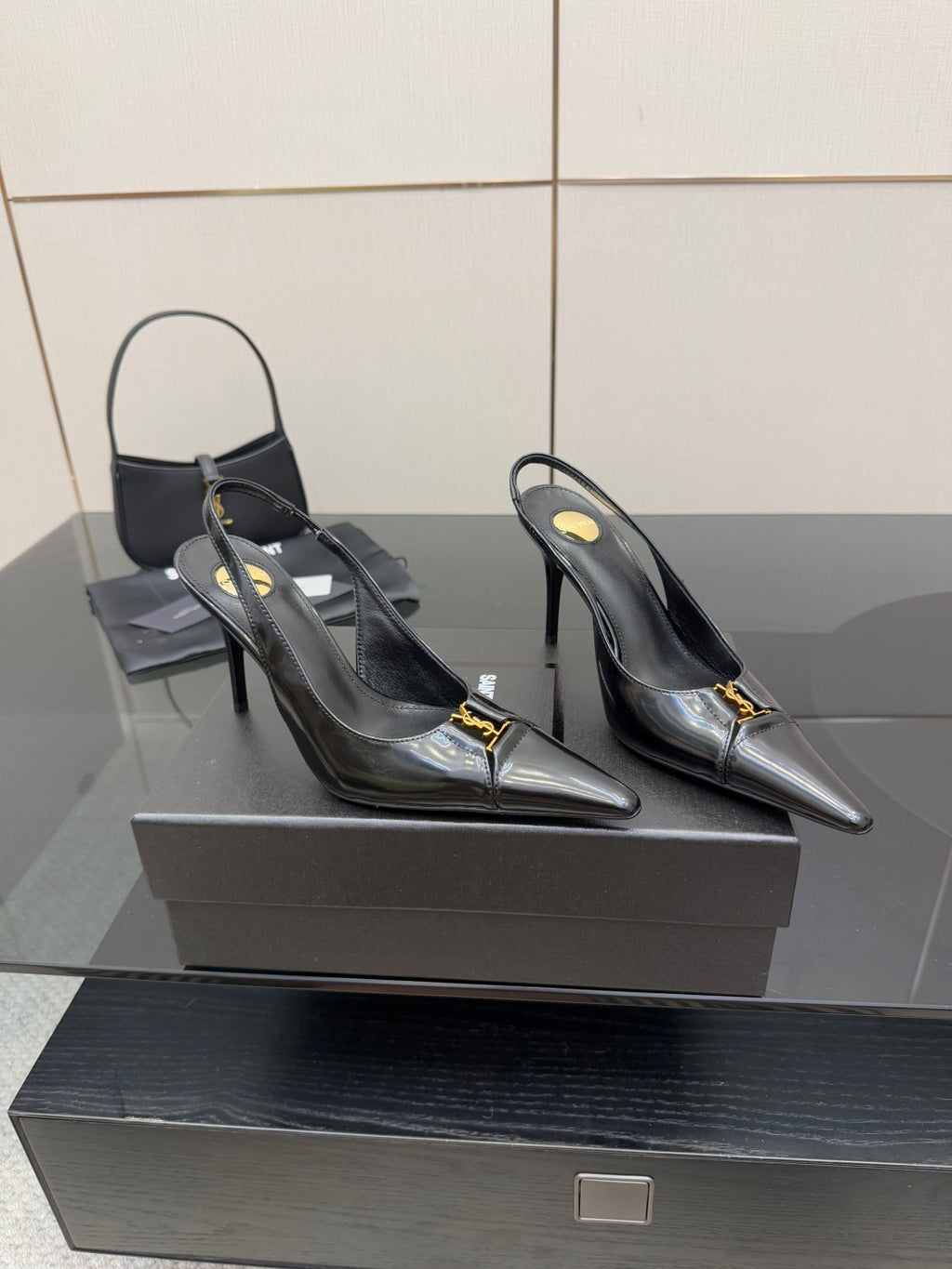 Black YSL slingback pumps with pointed toe, stiletto heel, gold emblem on strap
