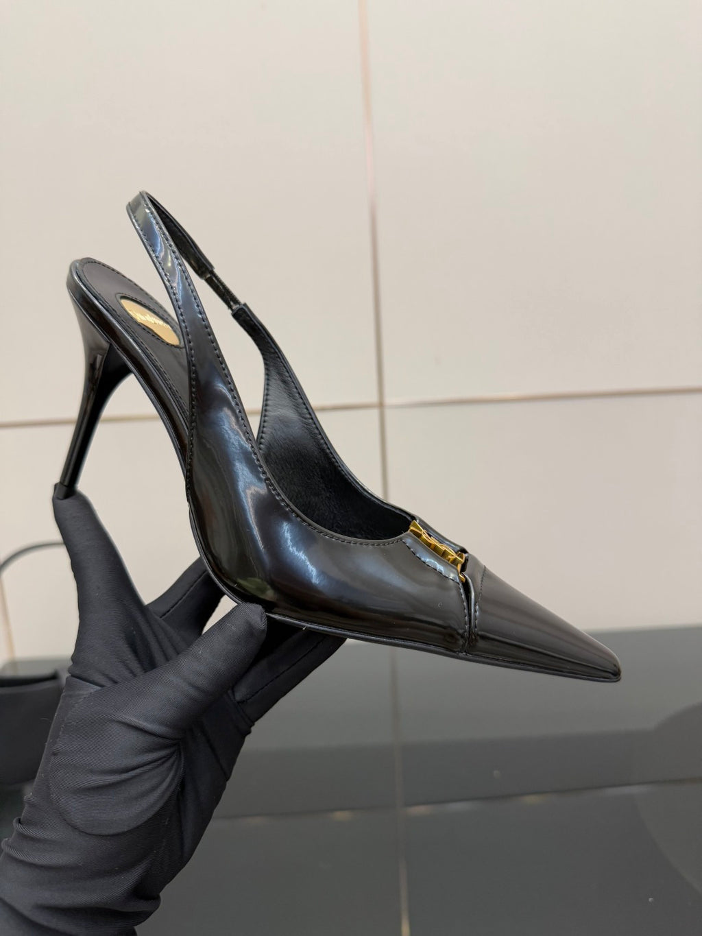Black YSL slingback pump close-up with pointed toe and stiletto heel, gold emblem