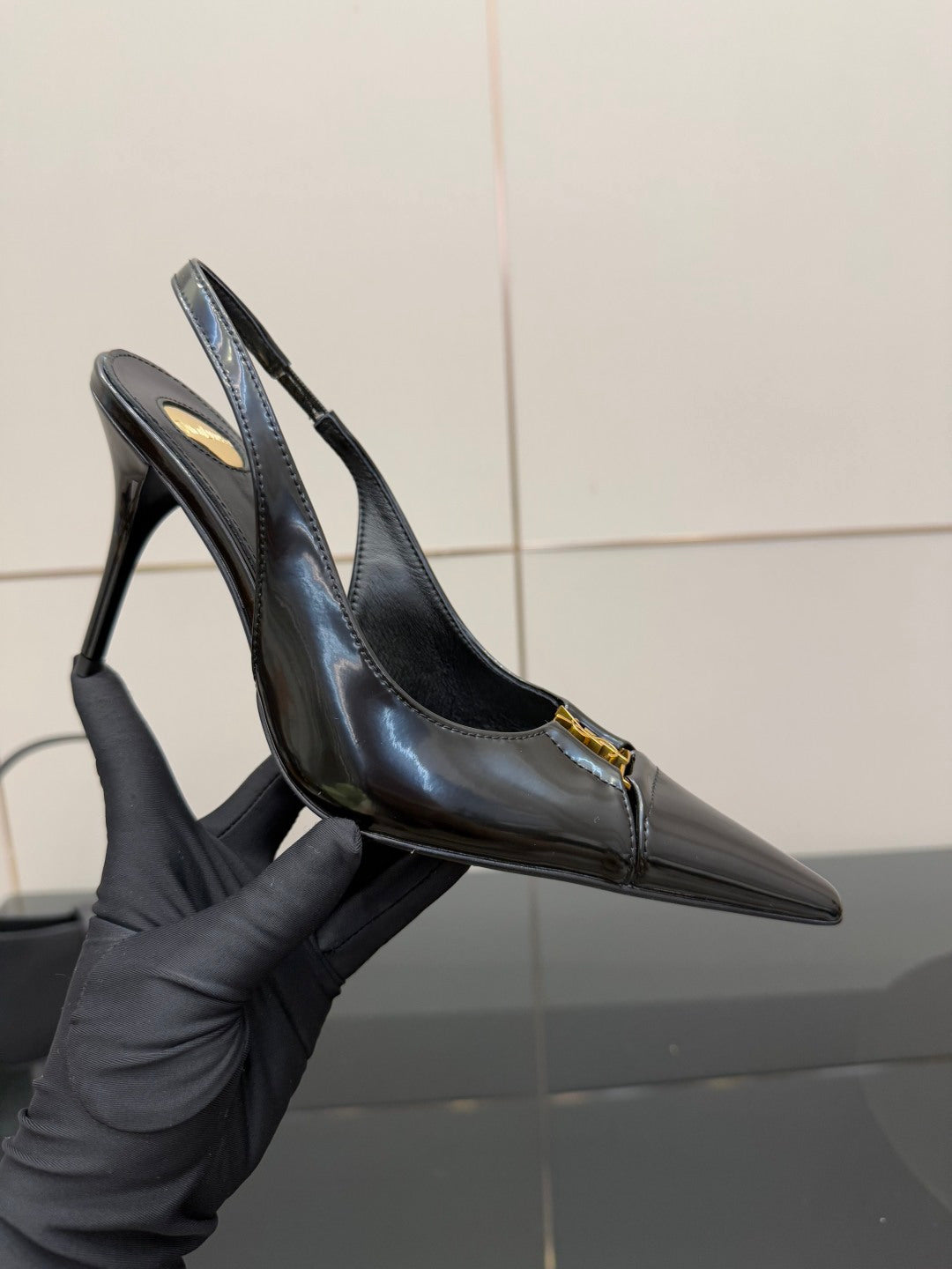Black YSL slingback pump close-up with pointed toe and stiletto heel, gold emblem
