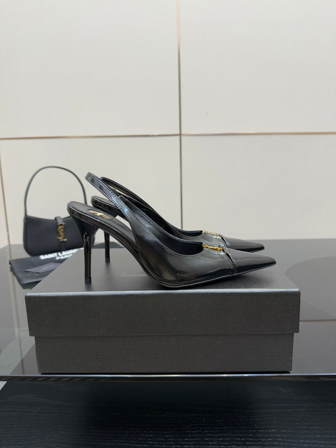 Black YSL slingback pump with pointed toe and tall stiletto heel, gold logo