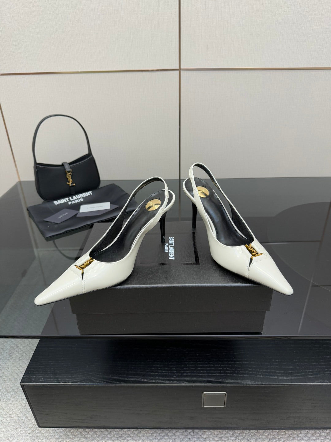 White pointed-toe slingback stiletto heels with black lining and small gold logo.