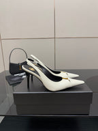 White pointed-toe slingback stiletto heels with black interior and gold logo hardware.