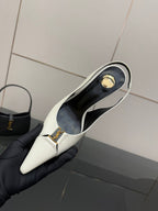 White slingback heel shoe opening with gold logo emblem and black lining, held up.